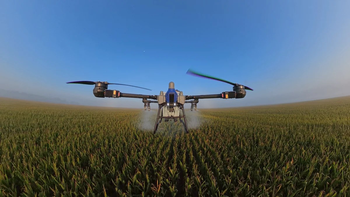 EAVision J150 agricultural spray drone spraying a Midwest corn field at low altitude
